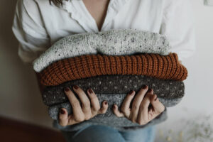 pile of sweaters in a woman's hands